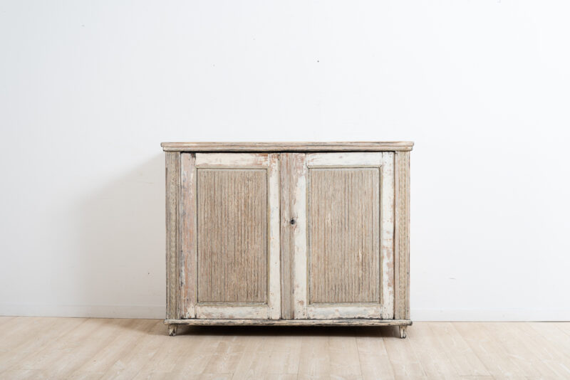 Provincial gustavian sideboard from Västerbotten in northern Sweden. Made around the year 1800. Fluted doors and angled corners with carved wooden decor. Dry scraped. Original working lock and key.