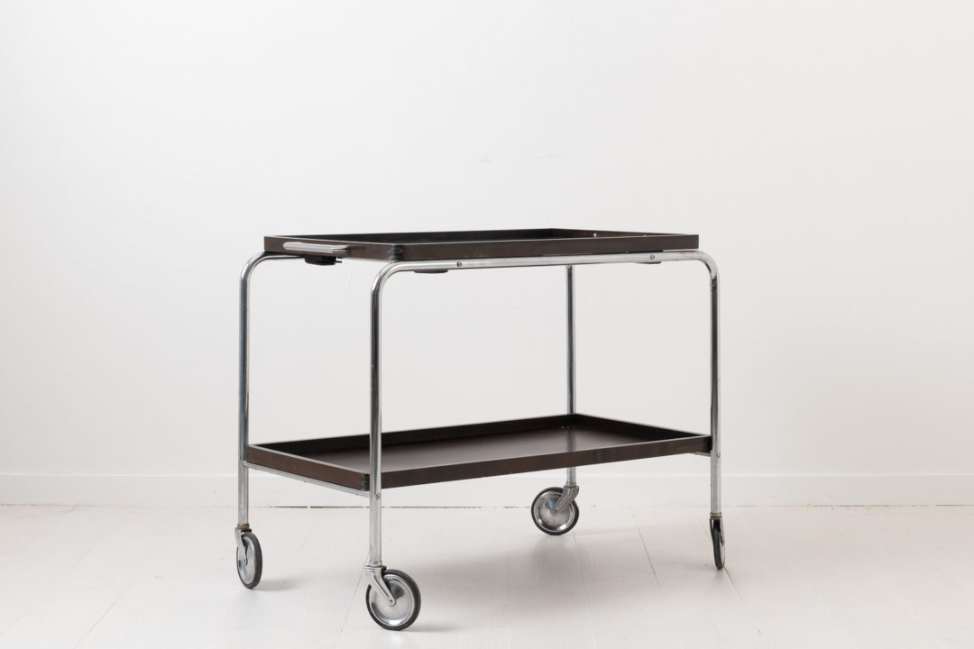 Art Deco bar cart from the 1930s. Frame made in nickel-plated metal with trays in dark stained wood. The tray have loose glass plates on top