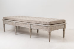 Low gustavian bench from Sweden. The bench is from the turn of the century 1700 to 1800. Made in painted pine with rich carved decorations.