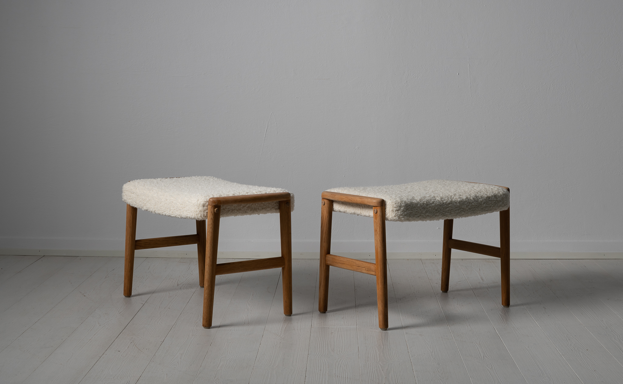 Scandinavian modern oak footstools from Sweden made around the 1960s. The stools are oak and newly upholstered. The cushions are upholstered with a special kind of white bouclé fabric