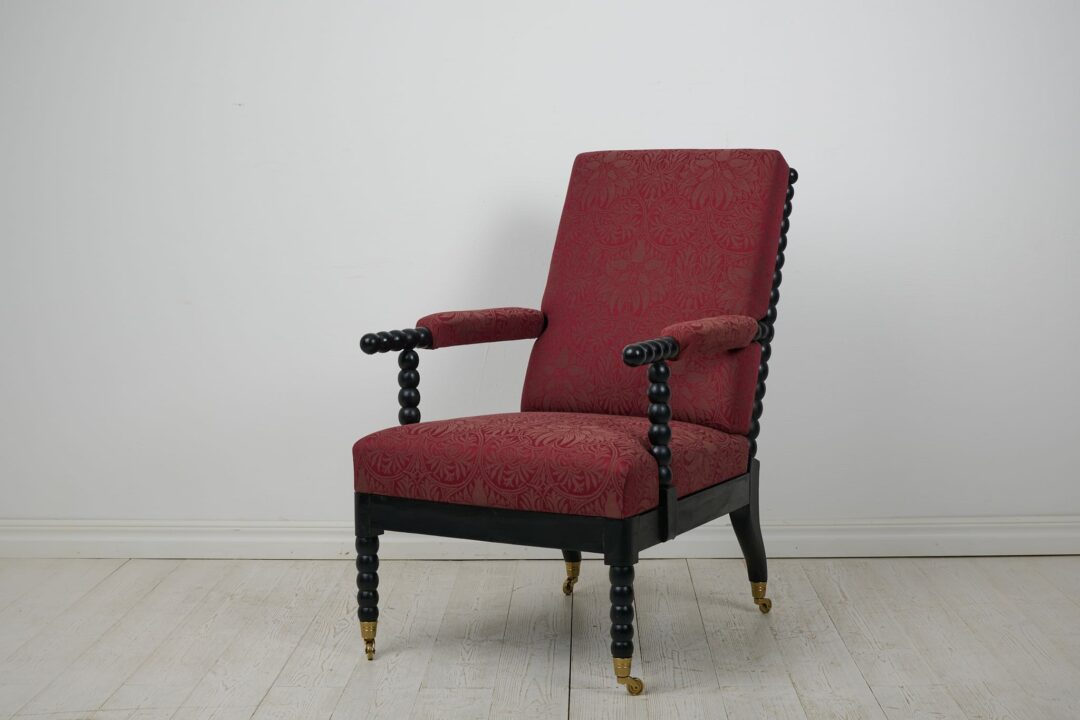 Antique Swedish spindle chair or lounge chair from the mid 1800s. The chair is comfortable and generous with a frame in blackened wood and a padded seat, back- and armrests.