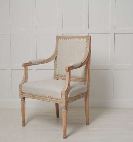 Swedish gustavian upholstered armchair from the late 18th century, circa 1790. The armchair has a straight shape with hand carved wooden decorations all over the chair. The decor spans around the backrest, down the armrest and around the seat itself, no space left forgotten. The chair has a regal and stately appearance with a touch of luxury, making it a statement piece to add to any space.

The armchair is steady with the original padding in the seat, back and armrests. Newly upholstered in a light toned and durable linen fabric that agrees well with the natural patina of the wood. Made in Swedish pine. Seating height is 45 cm.
