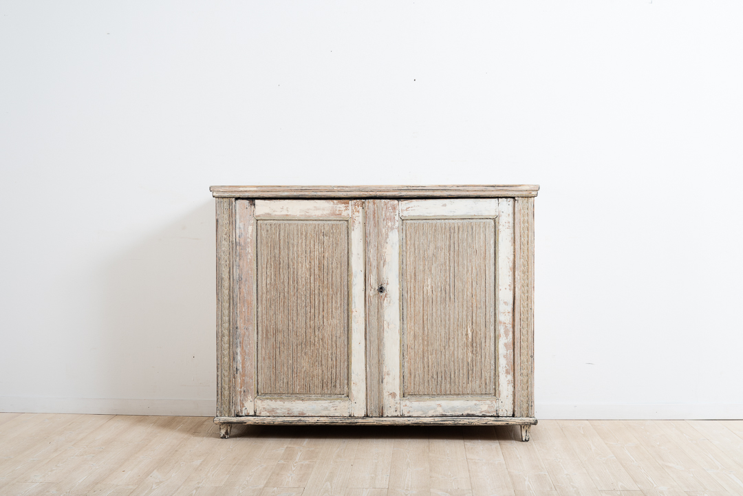 Provincial gustavian sideboard from Västerbotten in northern Sweden. Made around the year 1800. Fluted doors and angled corners with carved wooden decor. Dry scraped. Original working lock and key. 