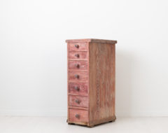 Unusual chest of drawers with seven drawers. The chest is tall and narrow with original wooden knobs on each drawer. Made in painted pine