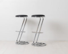 Scandinavian modern high stools with a z-shaped base in chrome and round black leather seats. Made during the second half of the 20th century.