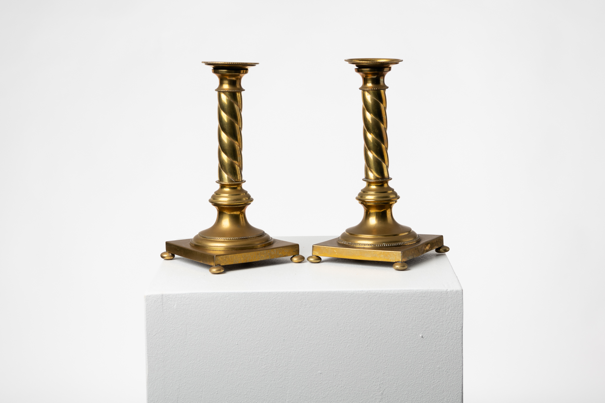  Swedish candle sticks in brass made during the later part of the 1800s. The pair are of the gustavian style with a square base, small round feet and a turned column