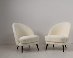 Scandinavian modern sheepskin chairs from the mid 20th century attributed to Arne Norell, Sweden. The chairs have an asymmetrical back and legs in stained birch