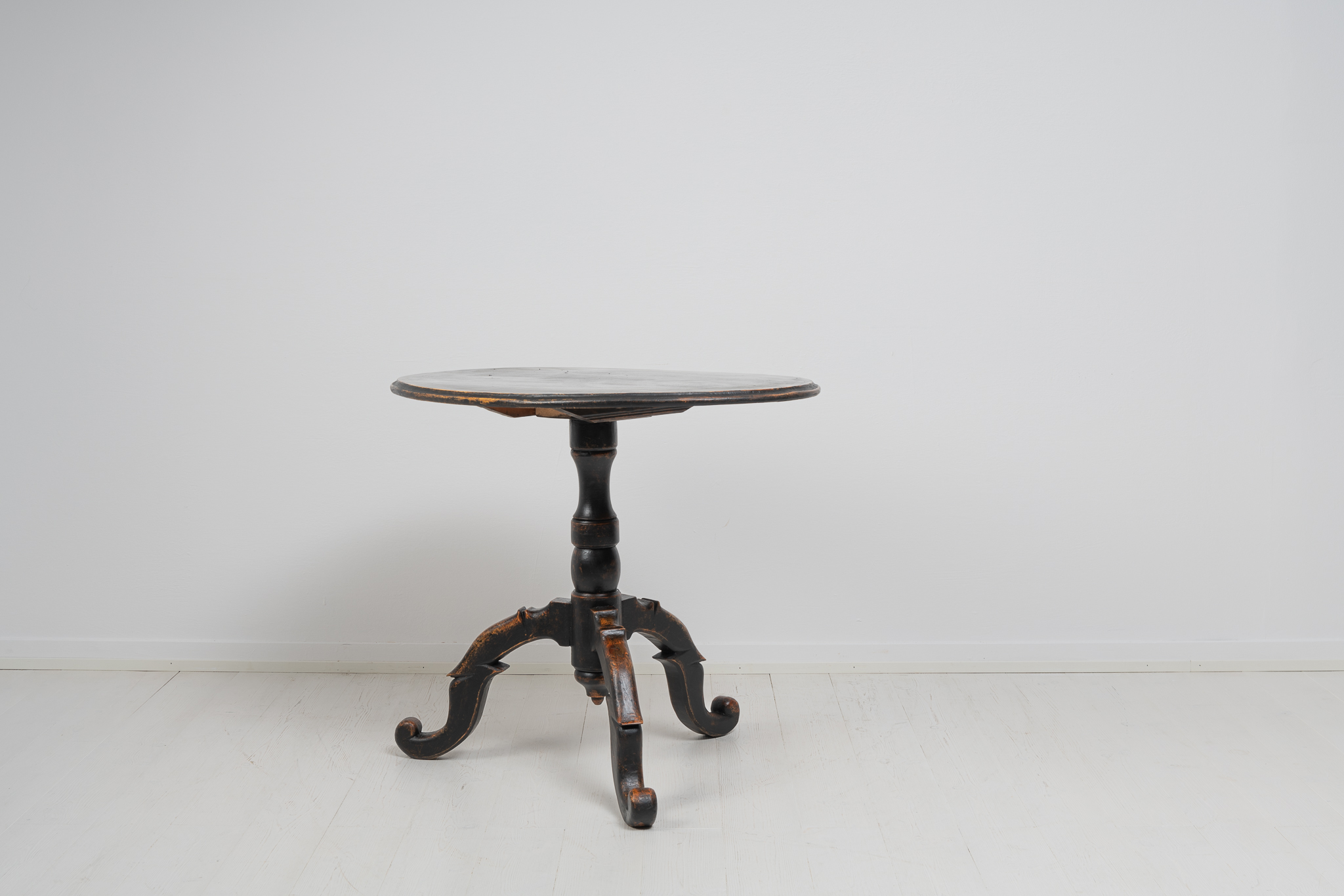 Small black tilt-top table from Sweden made during the mid 19th century, around 1860. The table is painted with black paint that has become distressed