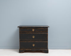 Black Swedish baroque chest of drawers from the late 1700s. The chest is painted pine with patina and distress that emphasises the shapes and contours