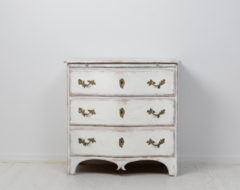 Light antique baroque commode from Sweden made during the late 1700s. The commode has a curved front and three drawers as well as an extra writing top