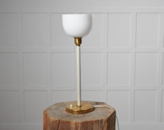 Swedish modern table light from the 1930s to 1940s. The light is likely by Böhlmarks SE. It has a foot in brass with a white stem.