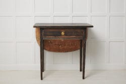Small antique black table in gustavian style from Sweden. The table is a genuine Swedish country house furniture from around 1820. The table has a rounded leaf table top