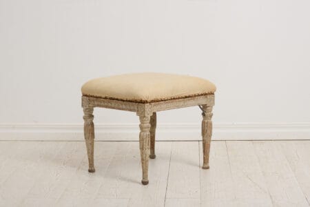 Genuine antique foot stool from the Swedish gustavian period around 1770 to 1780. This Swedish antique has classic carved wooden decor on the legs and sides.