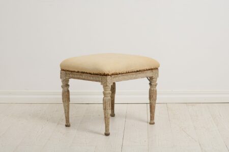 Genuine antique foot stool from the Swedish gustavian period around 1770 to 1780. This Swedish antique has classic carved wooden decor on the legs and sides.