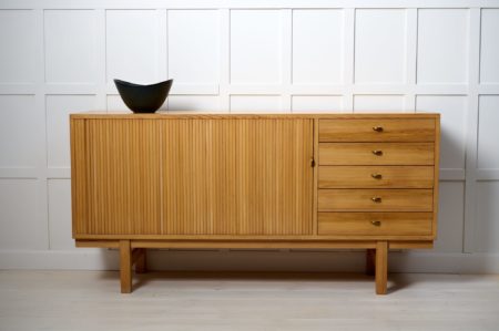 Swedish modern low sideboard from around 1960 to 1970. The sideboard is made in pine which is unusual to see. It has five drawers and a jalousie-door